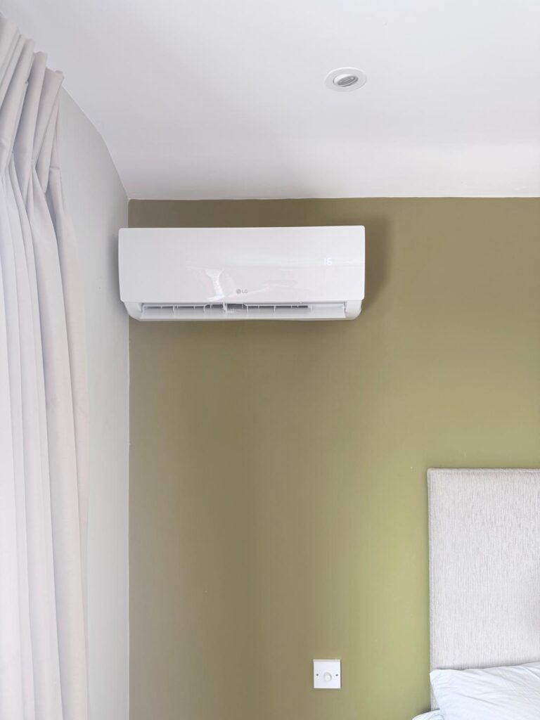 Wall-mounted air conditioning unit in a bedroom with a green wall